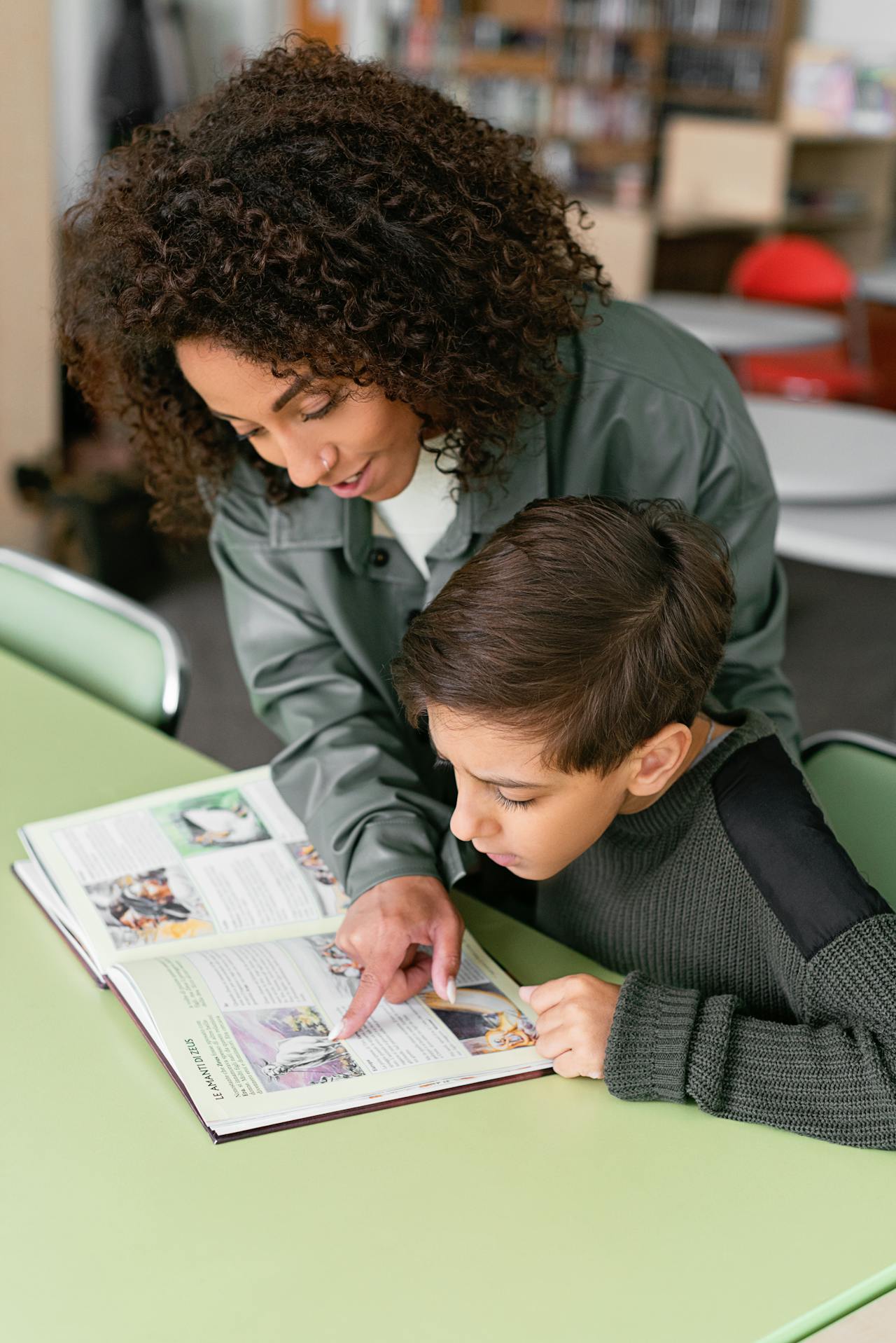 Educator reading a book one-on-one with a student at a school table